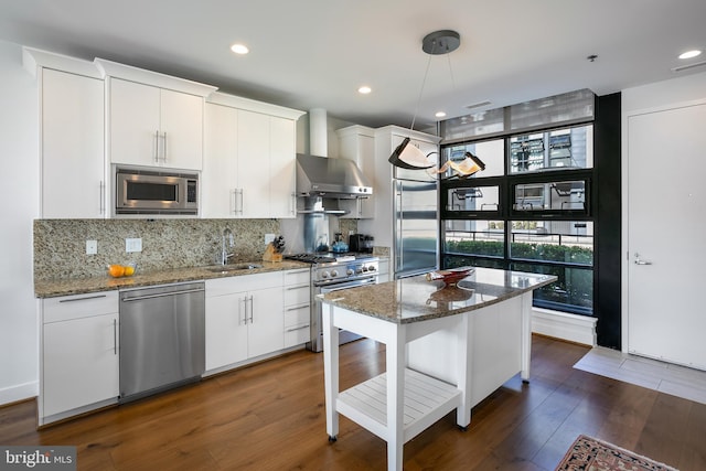 kitchen with built in appliances, light stone countertops, and white cabinetry