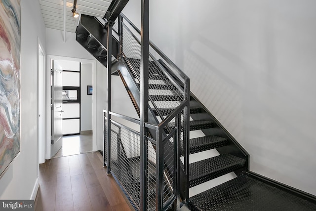 stairway featuring hardwood / wood-style flooring, beam ceiling, and wooden ceiling