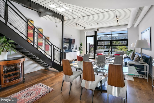 dining space featuring ceiling fan, dark hardwood / wood-style flooring, a wall of windows, and wine cooler