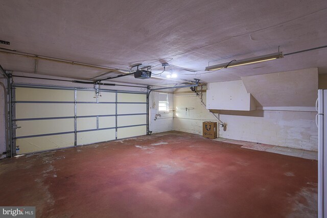 garage featuring a garage door opener and white refrigerator