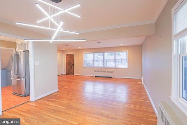 unfurnished living room featuring crown molding, radiator heating unit, a chandelier, and light wood-type flooring