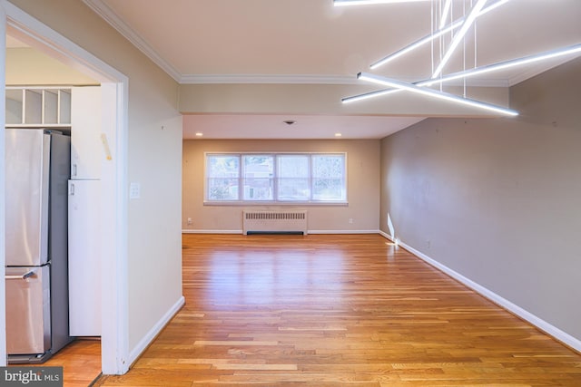 interior space featuring light hardwood / wood-style flooring, radiator heating unit, crown molding, and stainless steel fridge