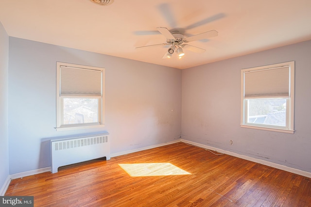 unfurnished room with plenty of natural light, radiator, hardwood / wood-style floors, and ceiling fan