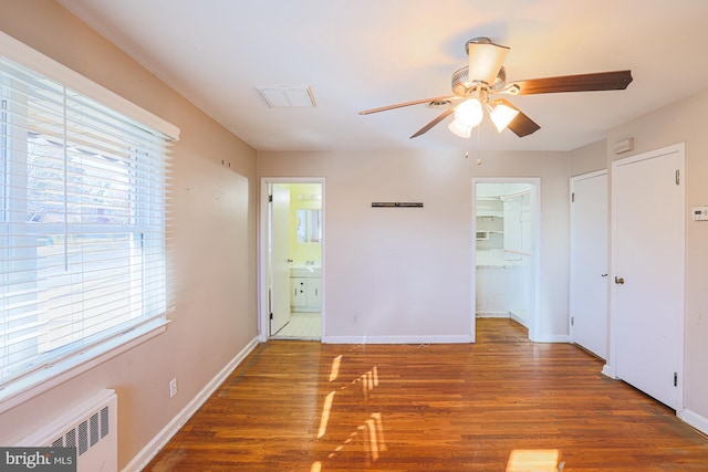 interior space with radiator, ceiling fan, ensuite bathroom, dark hardwood / wood-style flooring, and a walk in closet