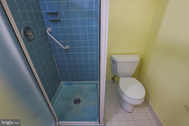 bathroom featuring tile patterned floors, toilet, and a shower with shower door