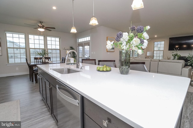 kitchen with sink, an island with sink, hanging light fixtures, and dishwasher