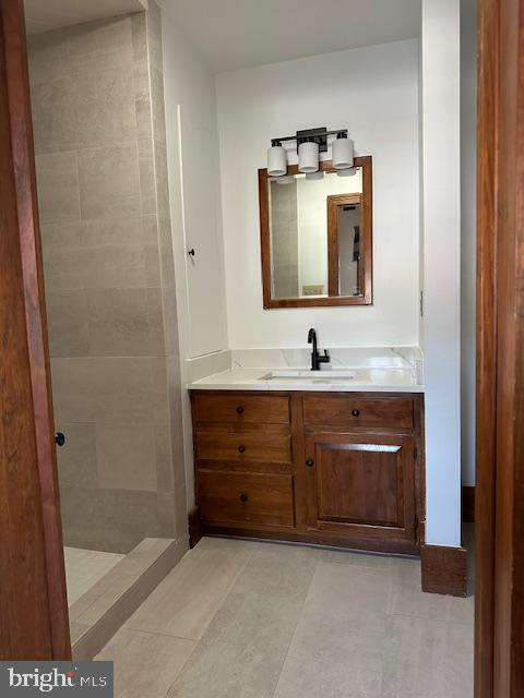 bathroom featuring a tile shower and vanity