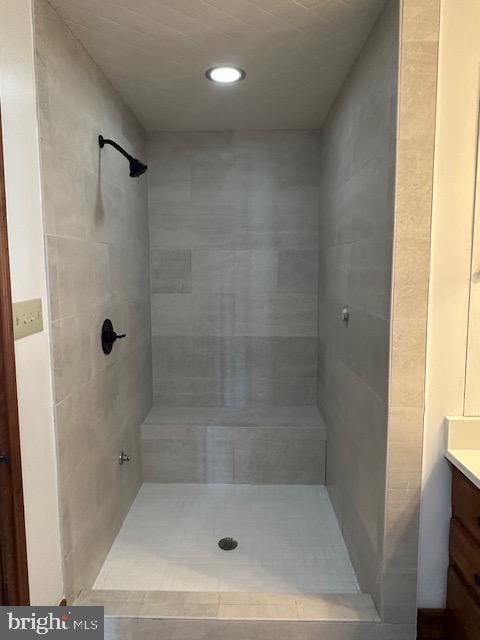 full bath with a tile shower and vanity