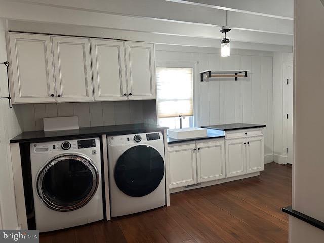 clothes washing area featuring a sink, cabinet space, washing machine and clothes dryer, and dark wood finished floors