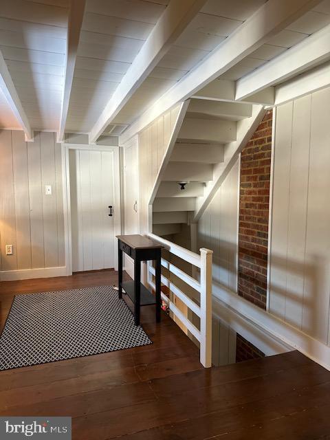 corridor featuring beam ceiling and wood finished floors