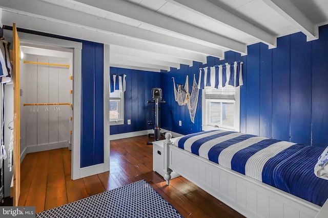 bedroom with wood-type flooring, baseboards, and beam ceiling