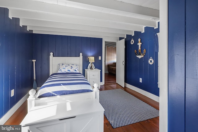 bedroom featuring wood finished floors, beam ceiling, and baseboards