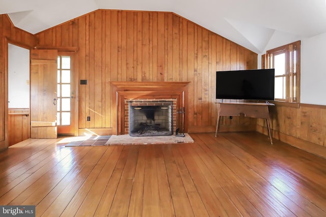 unfurnished living room featuring wood-type flooring, a fireplace, vaulted ceiling, and wooden walls