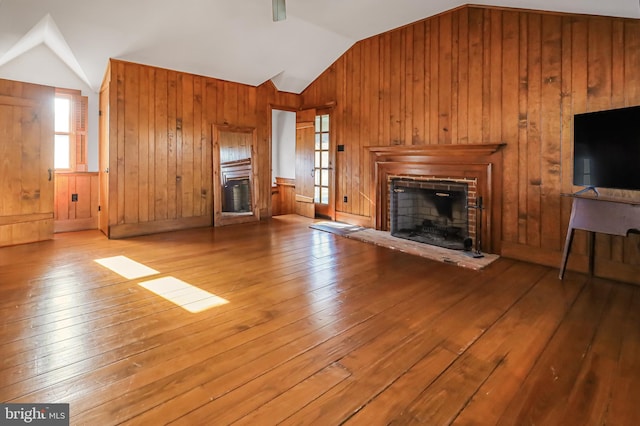 unfurnished living room with vaulted ceiling, a fireplace, and wood-type flooring