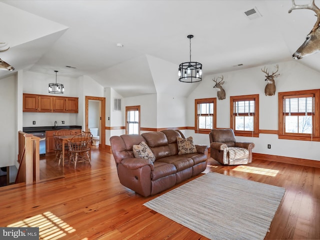 living area featuring light wood-type flooring, plenty of natural light, visible vents, and lofted ceiling