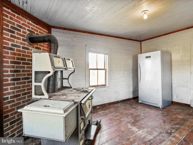 interior space with freestanding refrigerator, a wood stove, baseboards, and hardwood / wood-style flooring