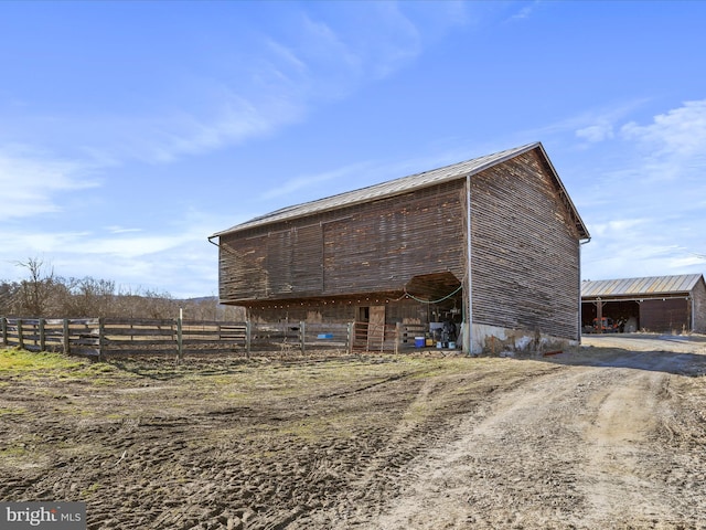 view of pole building with driveway and fence