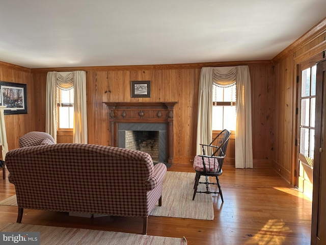 living area featuring wood walls, plenty of natural light, wood finished floors, and a high end fireplace