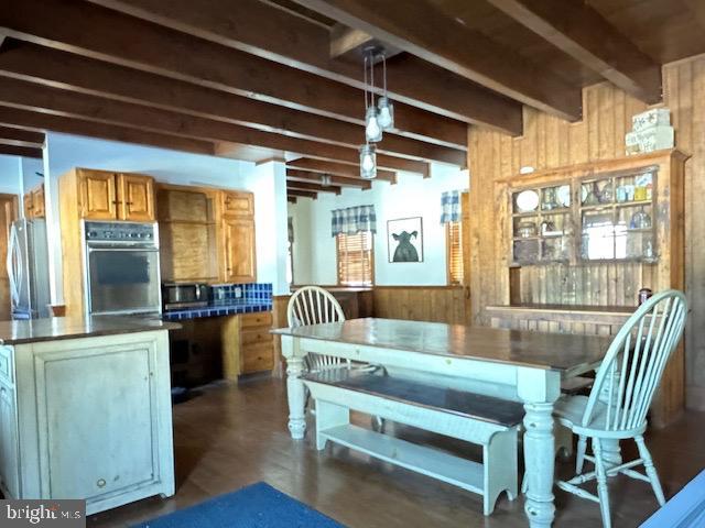 interior space featuring wood walls, wainscoting, and beam ceiling