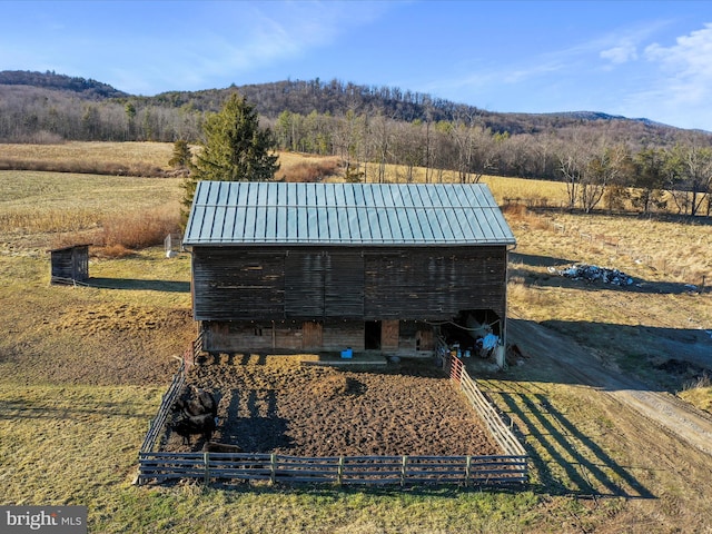 view of outbuilding featuring a rural view, a mountain view, and an outbuilding