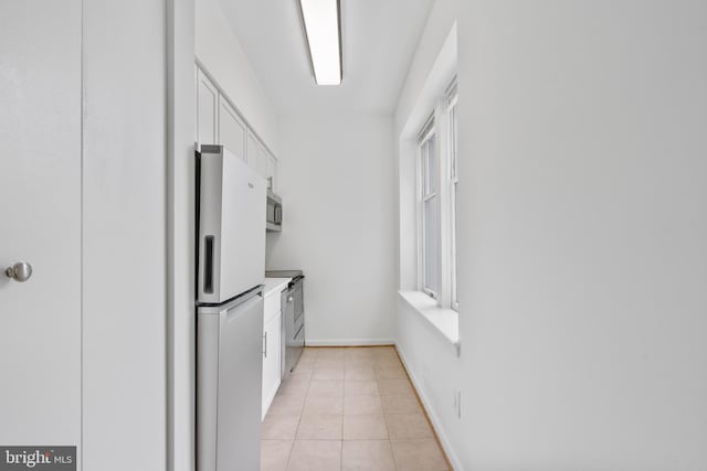 kitchen featuring stove, white cabinets, refrigerator, and light tile patterned floors