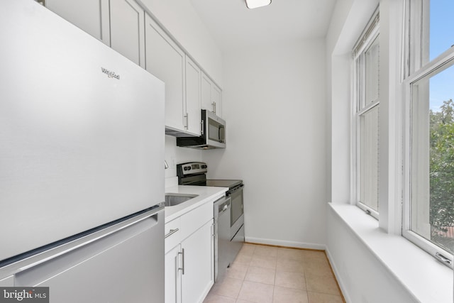 kitchen featuring appliances with stainless steel finishes, white cabinets, and light tile patterned floors