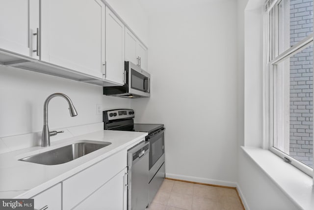 kitchen featuring white cabinets, appliances with stainless steel finishes, light tile patterned floors, and sink