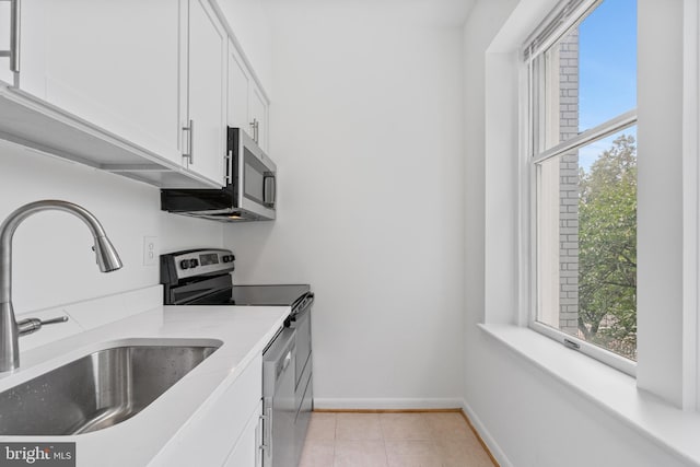 kitchen featuring stainless steel appliances, sink, white cabinets, light stone counters, and light tile patterned floors