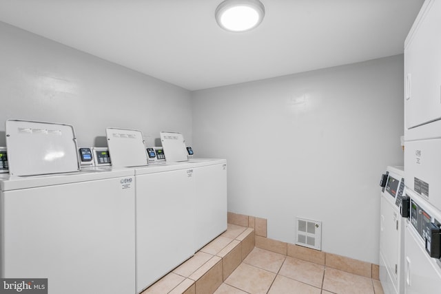 laundry area featuring washing machine and dryer, light tile patterned floors, and stacked washer / dryer