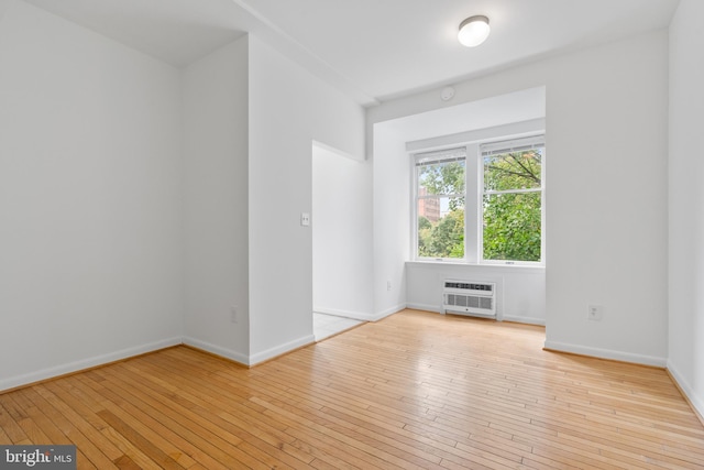 spare room featuring a wall unit AC and light hardwood / wood-style flooring