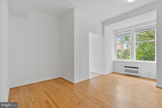 unfurnished room with a wall mounted AC and light wood-type flooring