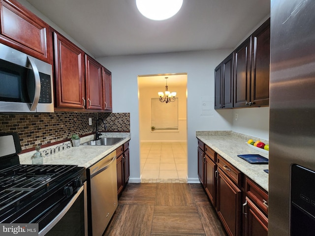 kitchen featuring decorative light fixtures, decorative backsplash, dark tile patterned flooring, appliances with stainless steel finishes, and sink