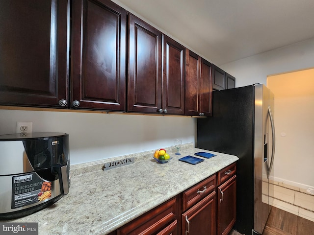 kitchen featuring tile patterned floors, light stone counters, and stainless steel refrigerator with ice dispenser