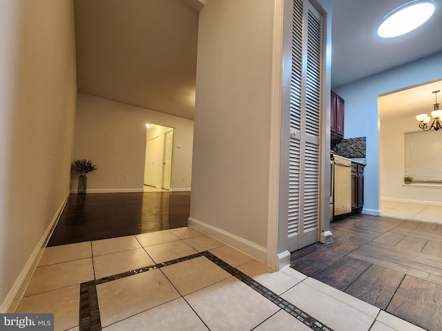 corridor with an inviting chandelier and light tile patterned flooring