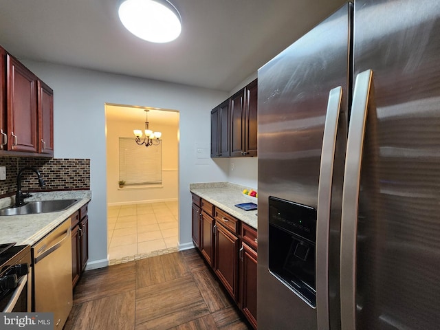 kitchen featuring a chandelier, appliances with stainless steel finishes, pendant lighting, decorative backsplash, and sink