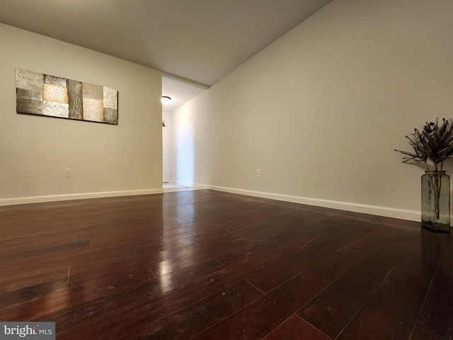 empty room featuring dark wood-type flooring and lofted ceiling