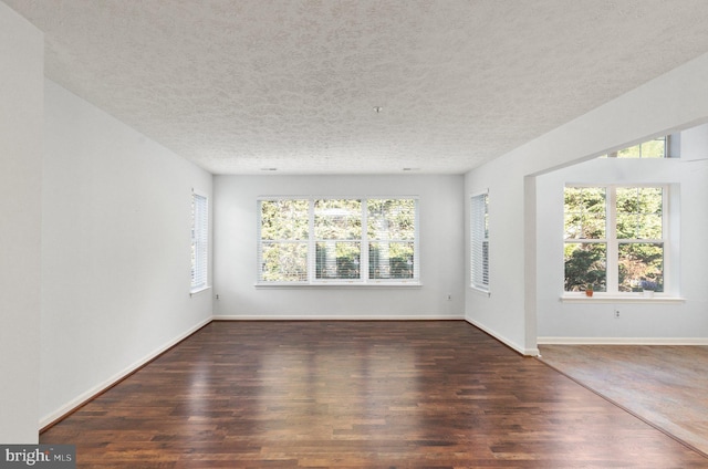 spare room with a textured ceiling and dark hardwood / wood-style flooring