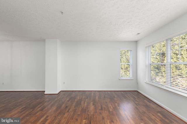 empty room featuring a textured ceiling and dark hardwood / wood-style floors