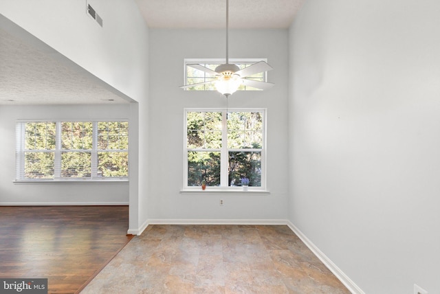 unfurnished dining area with a textured ceiling, ceiling fan, and a healthy amount of sunlight