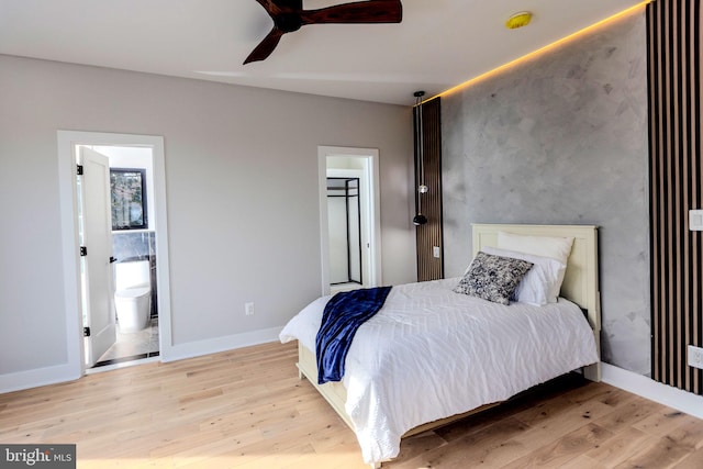 bedroom featuring ensuite bath, a walk in closet, light hardwood / wood-style floors, and ceiling fan