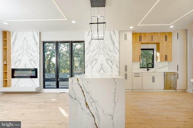 interior space with light brown cabinetry, plenty of natural light, light stone countertops, and white cabinets