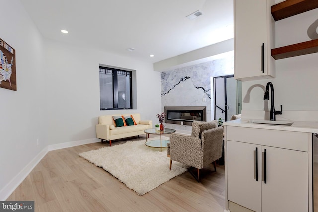 living room featuring a high end fireplace, sink, and light wood-type flooring