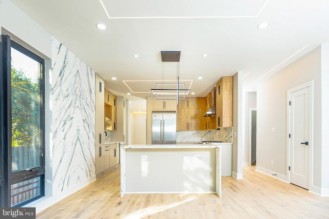 kitchen with built in fridge, decorative light fixtures, sink, decorative backsplash, and a center island