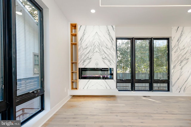 unfurnished living room featuring wood-type flooring and built in features