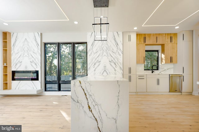 interior space featuring light brown cabinetry, a wealth of natural light, white cabinets, and light stone counters