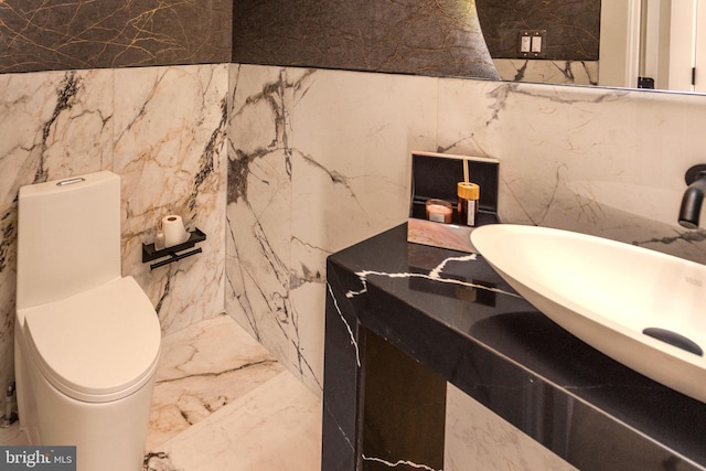 bathroom featuring sink, tile walls, and toilet