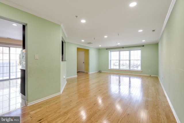 empty room with ornamental molding and light wood-type flooring