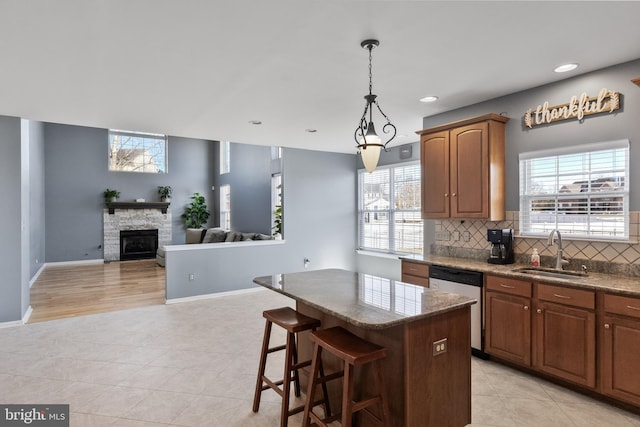 kitchen featuring stainless steel dishwasher, a healthy amount of sunlight, a center island, and sink