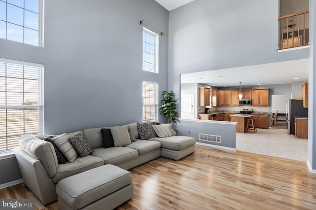 living room with a high ceiling, a wealth of natural light, and light hardwood / wood-style flooring