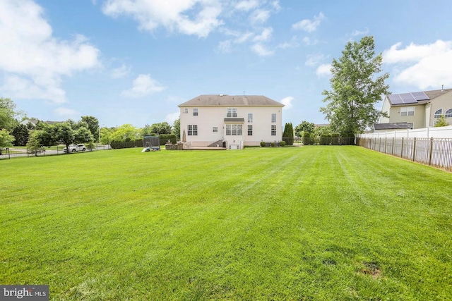 rear view of property featuring a trampoline and a yard